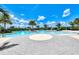 Expansive community pool with a central island, surrounded by lush palm trees and lounge seating at 11903 Alessandro Ln, Venice, FL 34293