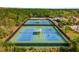 Aerial view of the community tennis courts with players surrounded by lush green landscaping at 11915 Tempest Harbor Loop, Venice, FL 34292