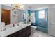 Charming bathroom with blue tiling in shower and tub, and a dark vanity with a marble countertop at 1212 Mango Ave, Venice, FL 34285