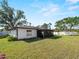 Exterior view of the home featuring the screened lanai and spacious backyard with mature trees and green grass at 1212 Mango Ave, Venice, FL 34285