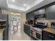 Modern kitchen featuring black cabinetry, stainless steel appliances, and tiled floors, seamlessly connected to the dining area at 1212 Mango Ave, Venice, FL 34285