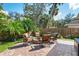 Backyard patio area with brick fire pit and seating, surrounded by lush landscaping and a wooden fence at 1232 Marilyn Ln, North Port, FL 34286