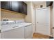 Bright laundry room featuring a washer, dryer, upper cabinets and a closed white door at 1232 Marilyn Ln, North Port, FL 34286