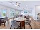 Well-lit dining area with multiple tables and chairs, ceiling fans, and sliding doors to a balcony at 128 Sea Anchor Dr, Osprey, FL 34229