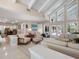 Open-concept living room featuring travertine flooring, a soaring ceiling, and sliding glass doors leading to the pool area at 128 Sea Anchor Dr, Osprey, FL 34229