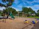 Outdoor playground with swings, slide and other equipment surrounded by mature trees and green space at 128 Sea Anchor Dr, Osprey, FL 34229