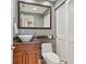 Cozy half-bath with wood vanity, marble countertop, stylish wallpaper, and a vessel sink at 128 Sea Anchor Dr, Osprey, FL 34229