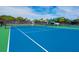 Wide angle shot of a blue tennis court and lush landscaping at 128 Sea Anchor Dr, Osprey, FL 34229