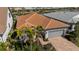 Aerial view of a well-maintained house with a tile roof, paved driveway, and beautifully landscaped front yard at 13194 Borrego St, Venice, FL 34293