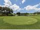 Picturesque golf course tee box with lush green grass, trees, blue skies and a water hazard at 1537 Monarch Dr, Venice, FL 34293