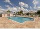 Community pool with lounge chairs, tables, manicured landscaping and a bright blue sky at 1537 Monarch Dr, Venice, FL 34293