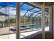 View of the pool and spa through the screened-in lanai with a protective black metal fence at 15804 29Th E St, Parrish, FL 34219