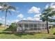 Picture of home's backyard showing the screened-in pool area, lush grass, and tropical landscaping at 1600 Lilliput Ct, Venice, FL 34293