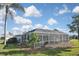 Backyard view showcasing a private screened in pool with manicured landscaping and partial blue skies at 1600 Lilliput Ct, Venice, FL 34293