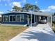 Charming blue home featuring a covered parking area, a well-manicured lawn, and large windows at 17 Nautical Dr, North Port, FL 34287