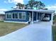 Charming blue home featuring a covered parking area, a well-manicured lawn, and large windows at 17 Nautical Dr, North Port, FL 34287