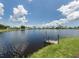 Relaxing lake view from the shoreline with a small dock for swimming and a distant view of neighborhood homes at 17 Nautical Dr, North Port, FL 34287