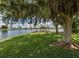 Scenic lake view featuring a large tree with Spanish moss hanging over picnic benches on a grassy lawn at 17 Nautical Dr, North Port, FL 34287