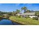 Backyard of a home overlooking a pond, featuring a screened in lanai, mature palms and lush green grass at 174 Southampton S Pl # 345, Venice, FL 34293