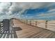 Perspective along a wooden fishing pier with railings, extending towards the ocean and beach at 174 Southampton S Pl # 345, Venice, FL 34293