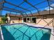 Backyard pool featuring clear blue water, a screened in enclosure, and access to the back of the house at 1773 Hudson St, Englewood, FL 34223