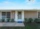 Front door with welcome mat and potted plants accenting the multiple window pane and neutral colors at 18053 Cullman Ave, Port Charlotte, FL 33948