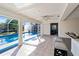 View of the tiled living area with pool access through glass sliding doors and access to another room at 18053 Cullman Ave, Port Charlotte, FL 33948