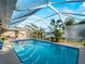 Screened pool with a clear blue sky view plus tropical landscaping beyond the screen at 18053 Cullman Ave, Port Charlotte, FL 33948