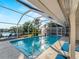 View of the pool and pool cage with palm trees and access to the living area at 18053 Cullman Ave, Port Charlotte, FL 33948