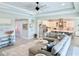 Open-concept living room featuring a large sectional sofa, tray ceiling with fan, and views of the kitchen and entry hall at 19836 Bridgetown Loop, Venice, FL 34293