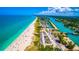 Aerial view of the stunning shoreline, turquoise waters, and lively beachgoers enjoying the sunny day at 200 Pameto Rd, Nokomis, FL 34275