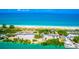 Expansive aerial view of a beach with lush greenery, convenient parking, and inviting turquoise waters at 200 Pameto Rd, Nokomis, FL 34275