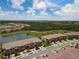 Aerial view of townhome community showing a lake, green space, and blue skies at 20390 Lagente Cir, Venice, FL 34293