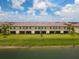 Aerial view of the back of townhomes, showing a lake and bright green grass at 20390 Lagente Cir, Venice, FL 34293