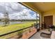 Screened patio with a view of the lake, lush green grass, and nearby buildings at 20390 Lagente Cir, Venice, FL 34293