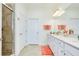 Bright bathroom featuring double sinks, white cabinetry, a large mirror, and a glass-enclosed shower with tiled walls at 23194 Banbury Way # 202, Venice, FL 34293