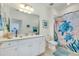 Well-lit bathroom features a white vanity, large mirror and shower with stylish, sea-life themed curtain at 23194 Banbury Way # 202, Venice, FL 34293