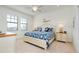 Well-lit bedroom featuring coastal decor, a ceiling fan, two windows, and bedside tables with lamps at 23194 Banbury Way # 202, Venice, FL 34293