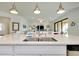 Stylish kitchen island with a stainless steel sink, pendant lights, and a view into the living area at 23194 Banbury Way # 202, Venice, FL 34293