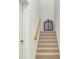 Carpeted staircase with wooden handrail, complemented by a cabinet at the top, adding a touch of elegance at 23194 Banbury Way # 202, Venice, FL 34293