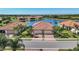 Aerial view of a home with a two-car garage, brick driveway, and community lake at 24065 Canterwood Way, Venice, FL 34293