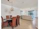 Open-concept dining area with a wicker dining set and decorative chandelier, leading into a naturally lit living room at 24065 Canterwood Way, Venice, FL 34293