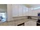 Stylish kitchen with white cabinets, granite countertops, and stainless steel dishwasher at 24065 Canterwood Way, Venice, FL 34293