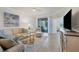 Bright living room featuring tile floors, a comfortable sofa, and sliding glass doors with lake view at 24065 Canterwood Way, Venice, FL 34293