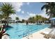 Large swimming pool with clear blue water, surrounded by palm trees, lounge chairs and blue sun umbrellas at 24065 Canterwood Way, Venice, FL 34293