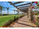 Picturesque walkway with pergola, manicured landscaping, and a view of the golf course at 24065 Canterwood Way, Venice, FL 34293