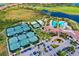 A high angle shot of a clubhouse, tennis courts and resort-style pool in lush, tropical landscaping at 24229 Spartina Dr, Venice, FL 34293