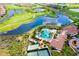 An aerial view of a community pool, clubhouse, tennis courts, and a green golf course at 24229 Spartina Dr, Venice, FL 34293