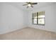 A clean, bright bedroom with neutral carpet, a ceiling fan, and a window at 24229 Spartina Dr, Venice, FL 34293