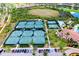 Aerial view of meticulously maintained tennis courts surrounded by lush landscaping and neighborhood homes at 24229 Spartina Dr, Venice, FL 34293